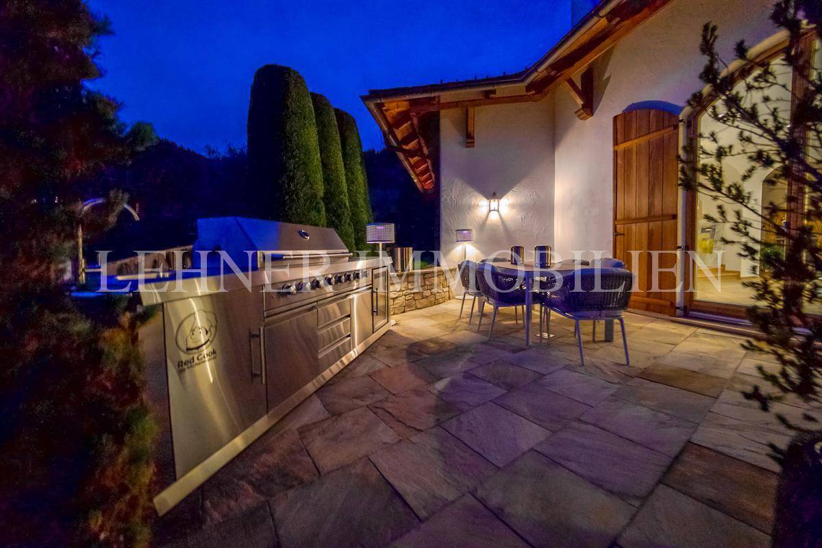 Exklusive Außenküche mit großem Grill und Essbereich auf der Terrasse, perfekt für gesellige Abende.
