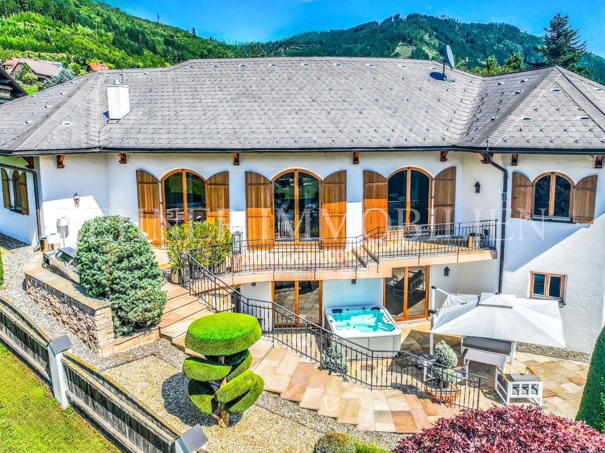 Luftaufnahme der Rückseite des Hauses mit großer Terrasse, Whirlpool und gepflegtem Gartenbereich.