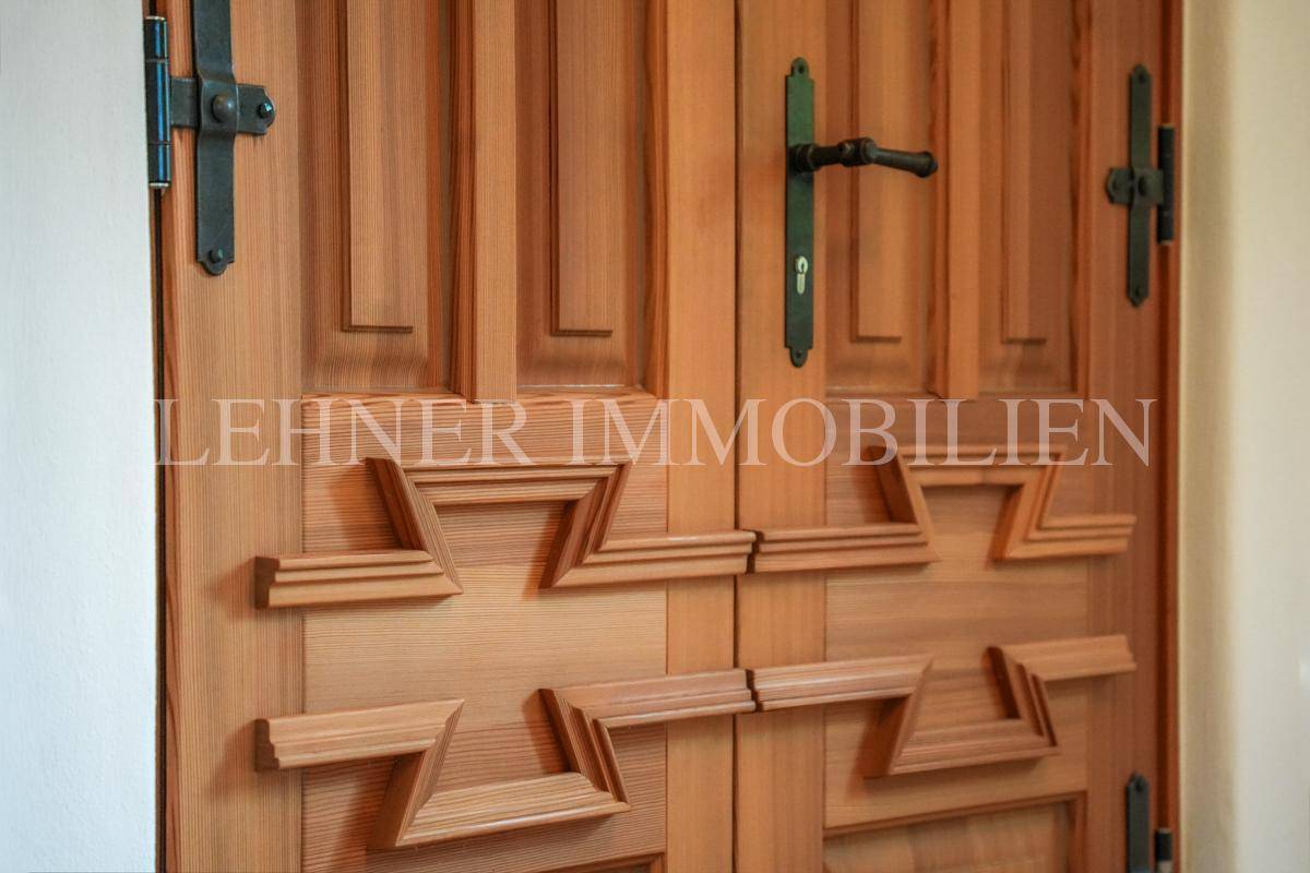 Detailansicht einer massiven Holztür mit traditionellen Schnitzereien und Beschlägen.