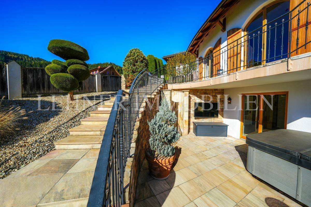Helle Terrasse mit Whirlpool und eleganten Stufen, die zum oberen Bereich des Gartens führen.
