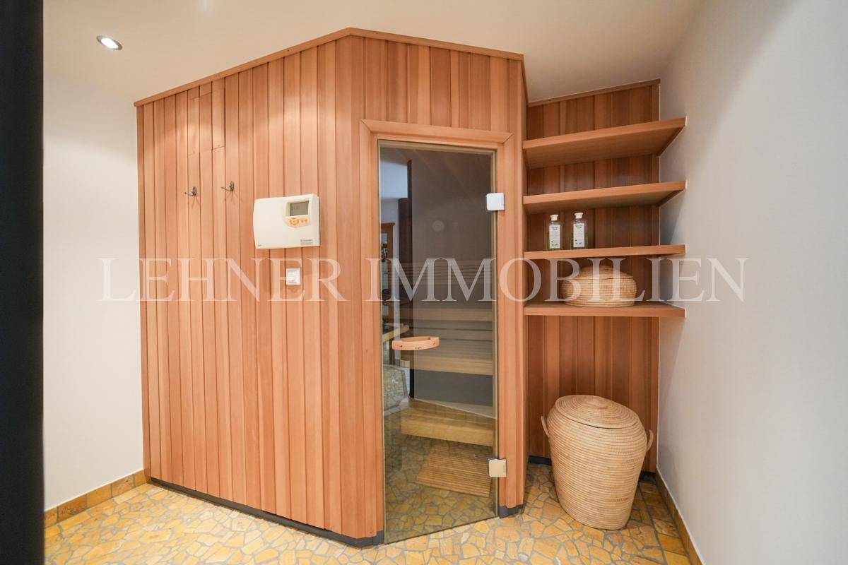Moderne Saunakabine aus Holz mit Glastür und integrierten Regalen im Wellnessbereich.
