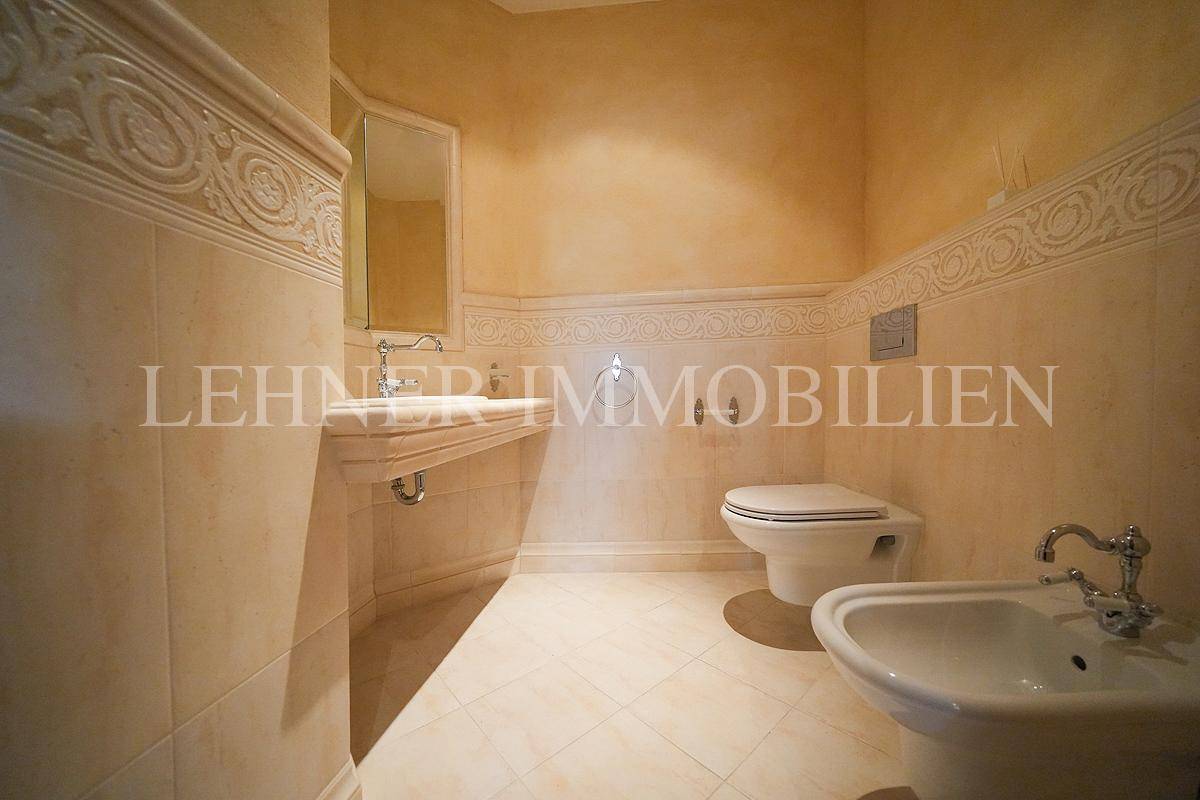 Stilvolles Gäste-WC mit Bidet, Wand-WC und einem einzelnen Waschbecken, umgeben von dekorativen Fliesen.