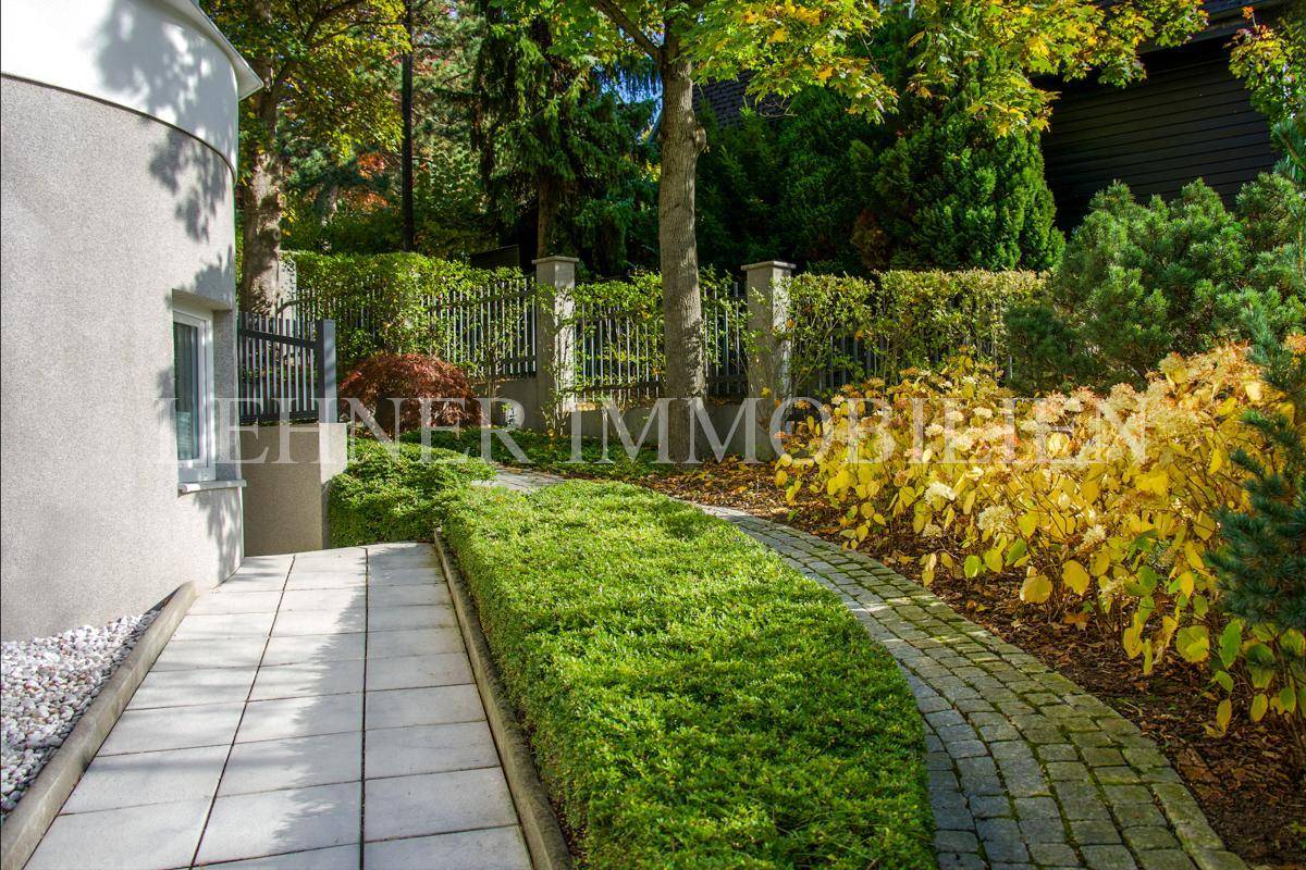 Gepflegter Gartenweg entlang der Hausseite, umgeben von üppiger Bepflanzung.