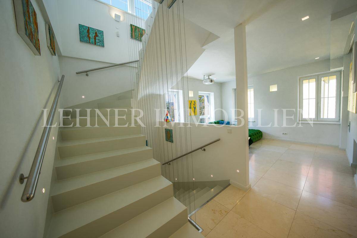 Moderne Treppe mit schwebenden Stufen und Seilgeländer, die zum hellen Wohnbereich führt.
