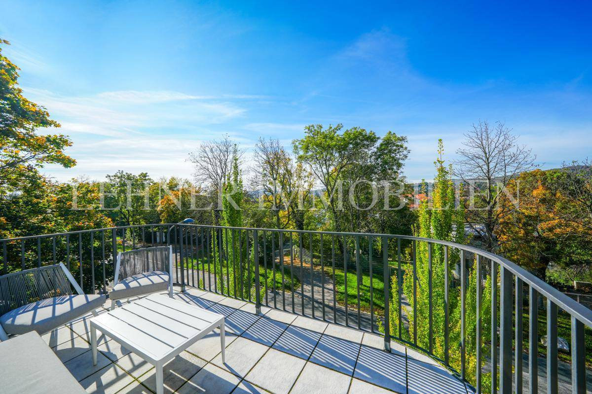 Geräumiger Balkon mit Sitzgelegenheiten, umgeben von Bäumen und mit einem schönen Ausblick.