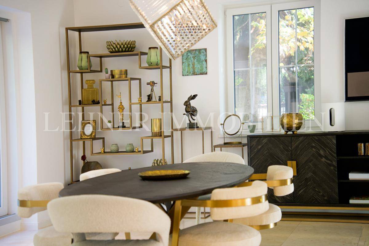 Stilvoller Essbereich mit Design-Regal, dekorativen Objekten und Blick in den Garten.