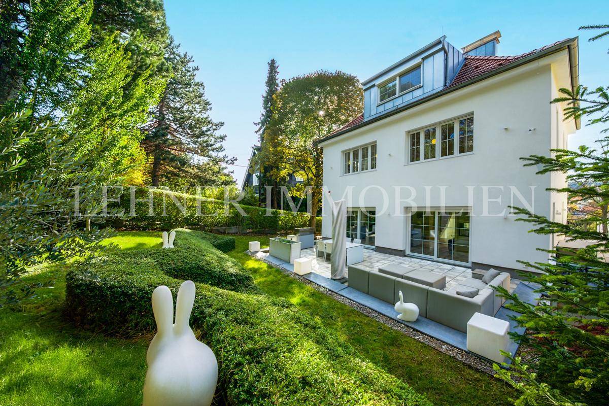 Gepflegter Garten mit Terrasse, Lounge-Möbeln und dekorativen Elementen vor der Villa.