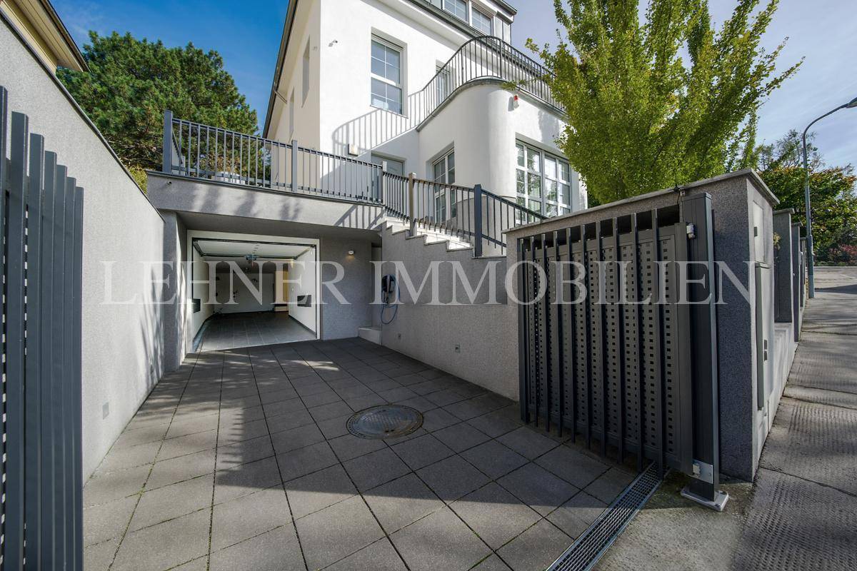 Moderne Einfahrt mit Garagenzugang und Außentreppe zum Haupteingang des Gebäudes.