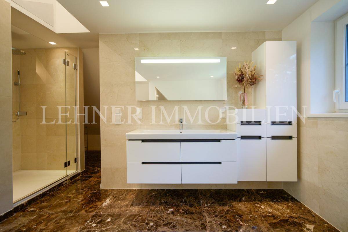 Modernes Badezimmer mit großem Waschtisch, Spiegelschrank und begehbarer Dusche auf Marmorboden.