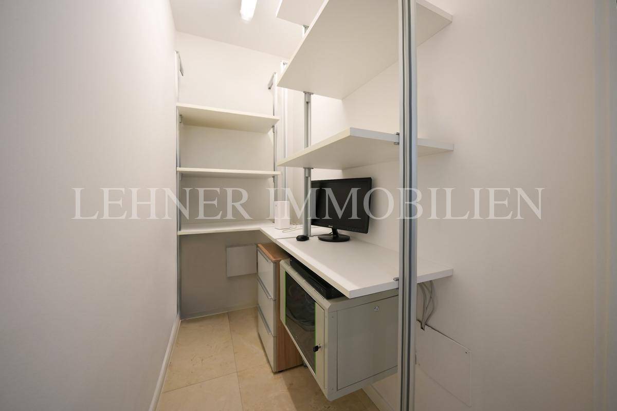 Kleiner Arbeitsbereich mit Regalen, Schreibtisch und Monitor, ideal als Home-Office oder Abstellraum.
