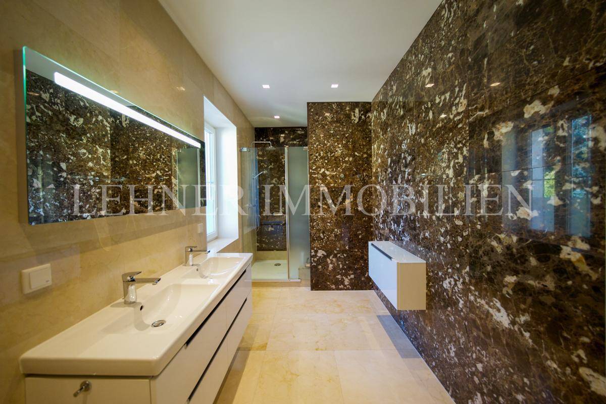 Elegantes Badezimmer mit großem Doppelwaschbecken, begehbarer Dusche und hochwertigen Marmoroberflächen.