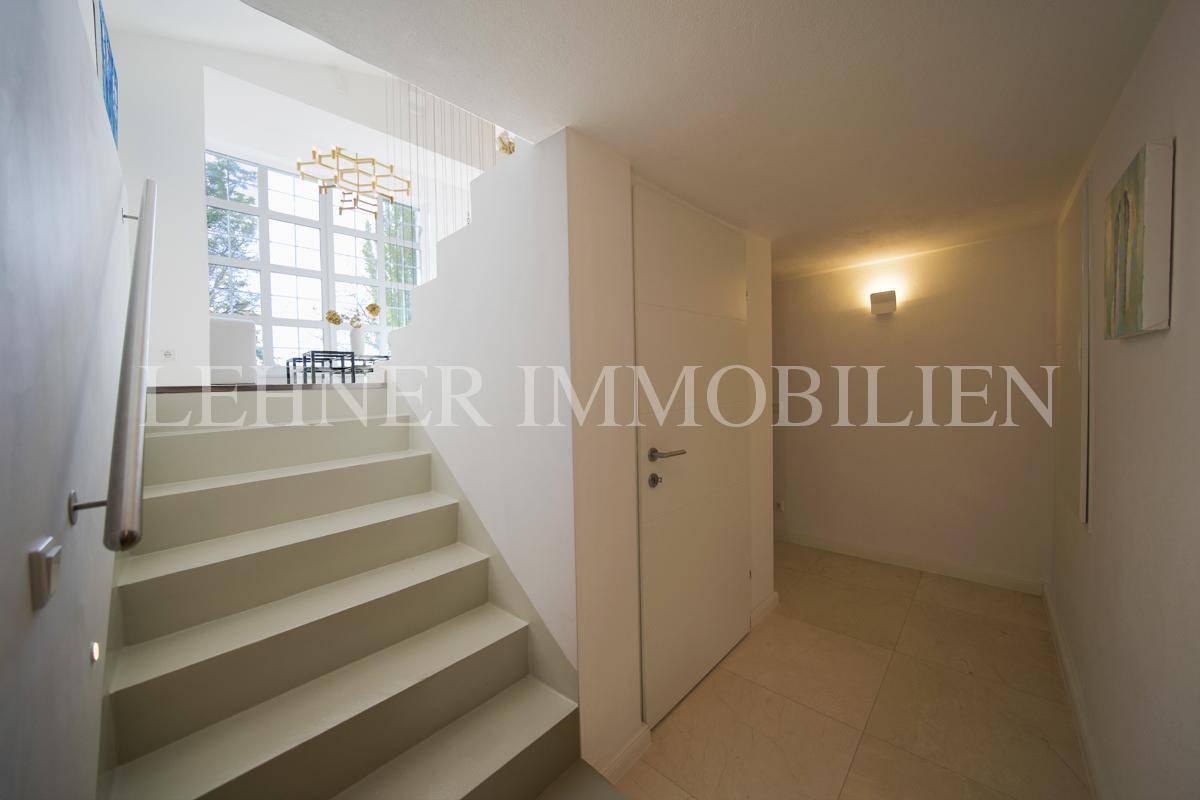 Heller Eingangsbereich mit moderner Treppe und Zugang zum Wohnbereich, ausgestattet mit Fliesenboden.