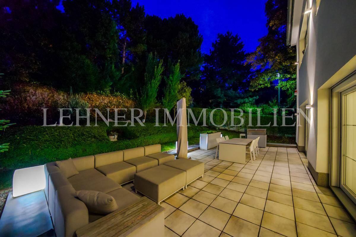 Die weitläufige Terrasse mit modernen Möbeln und indirekter Beleuchtung, ideal für Abende.