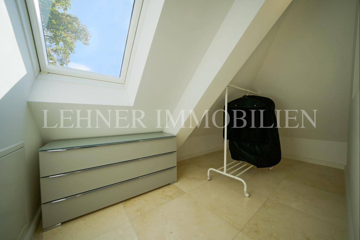 Heller Ankleidebereich im Dachgeschoss mit Dachfenster, Kommode und Kleiderstange unter der Dachschräge.
