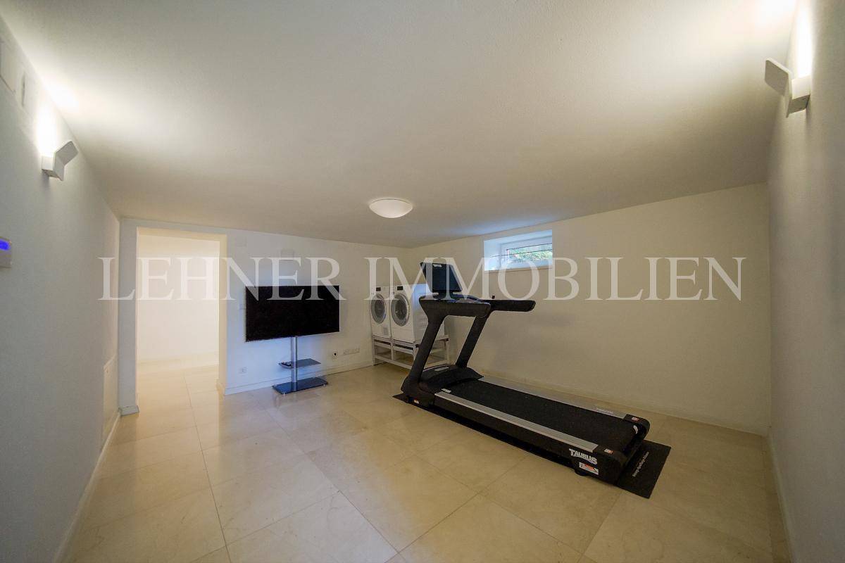 Fitnessraum im Untergeschoss mit Laufband und Fernseher, ideal für das tägliche Training.
