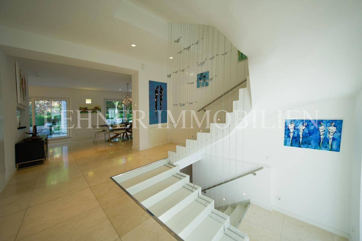 Offener Eingangsbereich mit eleganter Treppe, der in den Essbereich mit Gartenzugang übergeht.