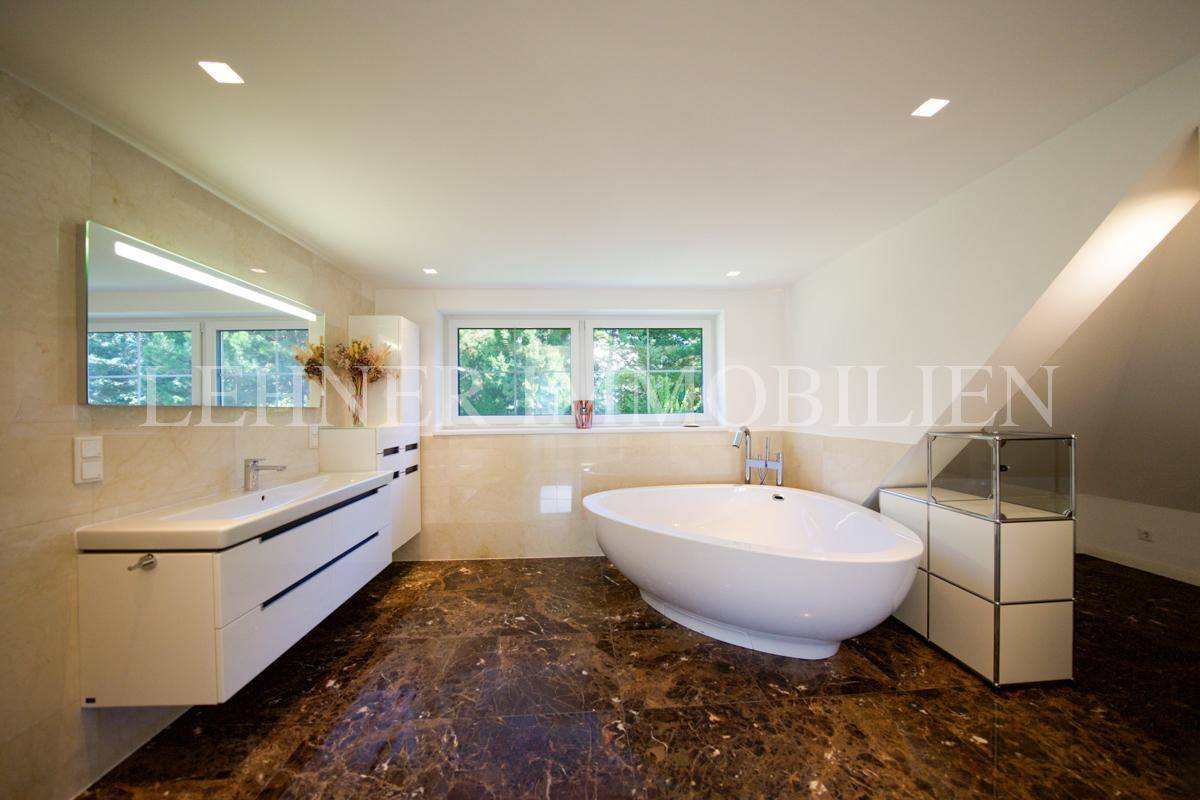 Helles Badezimmer mit freistehender Badewanne, großem Fenster und modernem Waschtisch unter der Dachschräge.