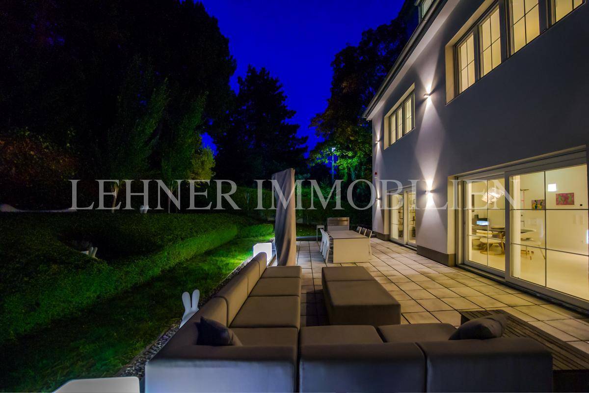 Geräumige Terrasse mit Lounge-Bereich und Essplatz, umgeben von grüner Bepflanzung.