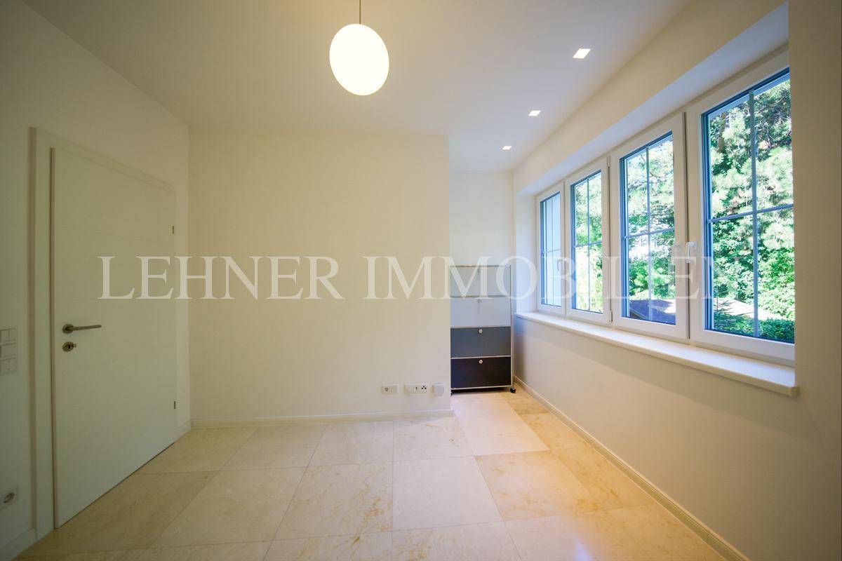 Helles Zimmer mit großen Fenstern, die einen schönen Ausblick bieten, und modernem Fliesenboden.