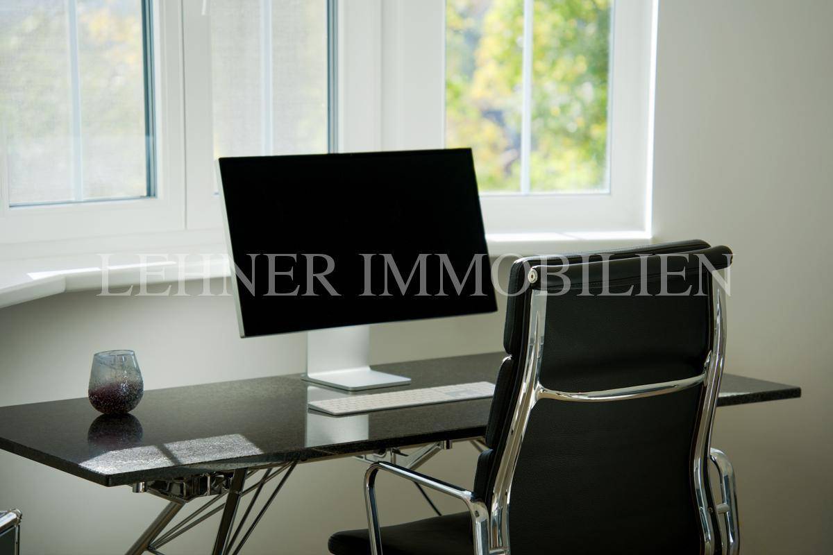 Detailansicht des Arbeitsplatzes mit modernem Schreibtisch, Bürostuhl und Blick ins Grüne.