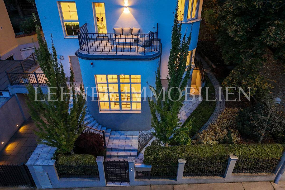 Ansicht der Stadtvilla von oben mit Eingangsbereich, Balkon und gepflegter Hecke.