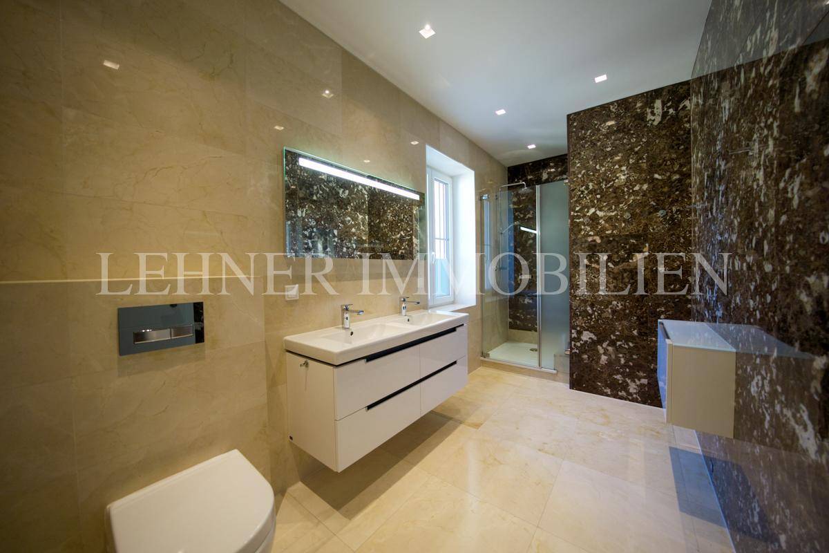 Luxuriöses Badezimmer mit Doppelwaschbecken, moderner Dusche und eleganten Marmorfliesen.