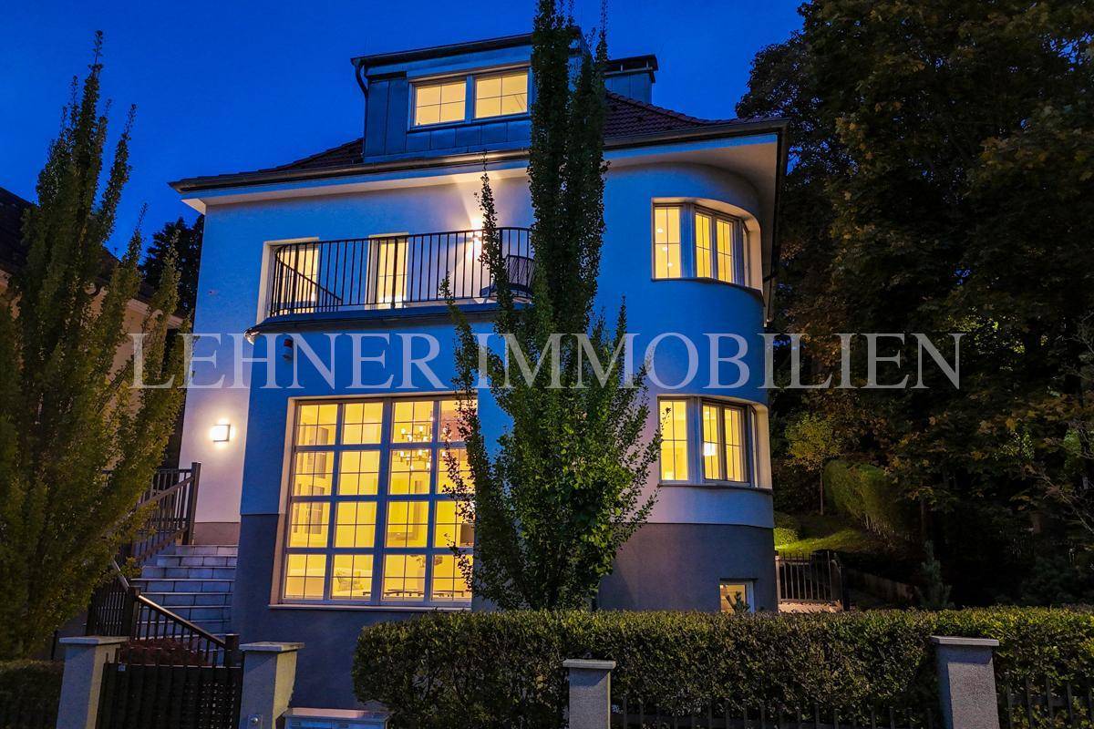 Elegante Stadtvilla bei Nacht mit beleuchteten Fenstern und Balkon.