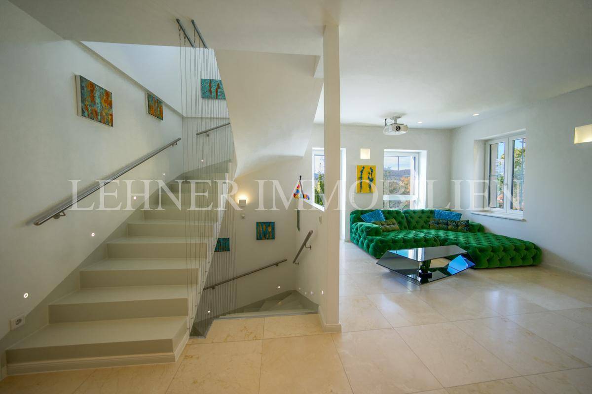 Geräumiges Wohnzimmer mit auffälligem grünem Sofa, modernem Couchtisch und Blick auf die offene Treppe.