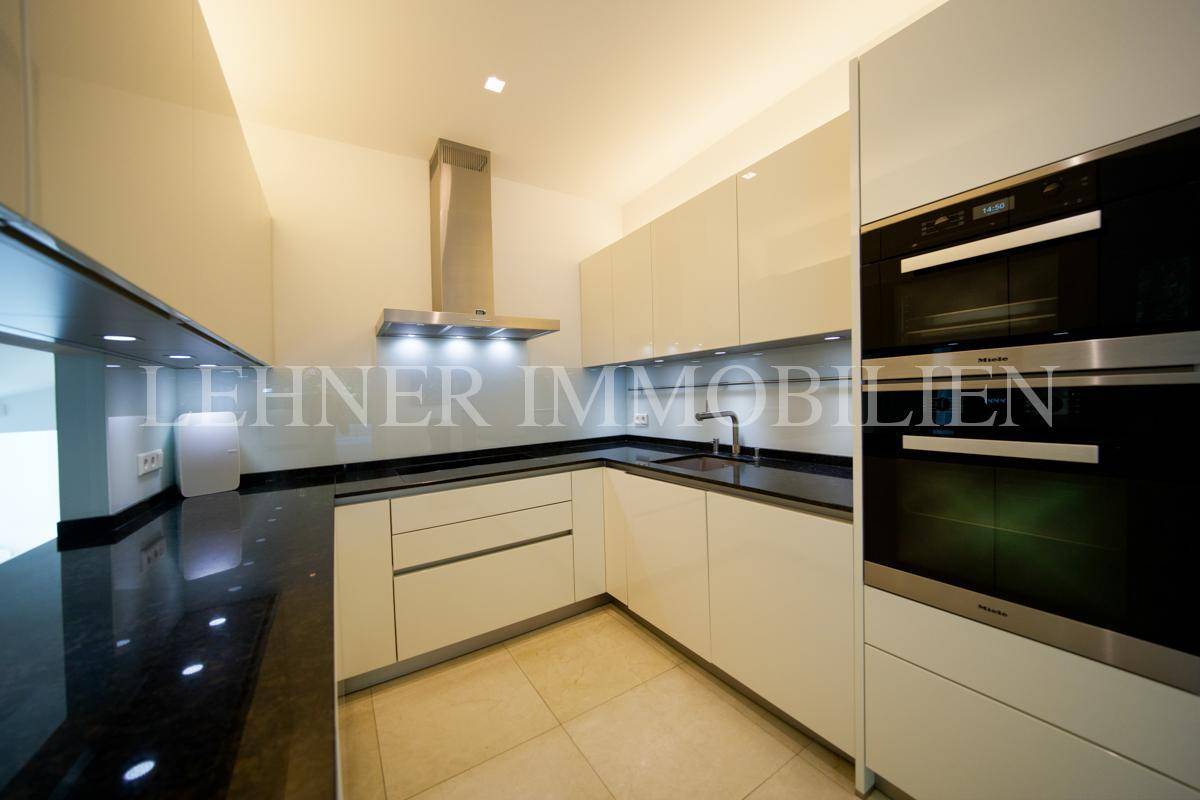 Elegante Einbauküche mit Miele-Geräten, schwarzer Granit-Arbeitsplatte und integrierter Beleuchtung.