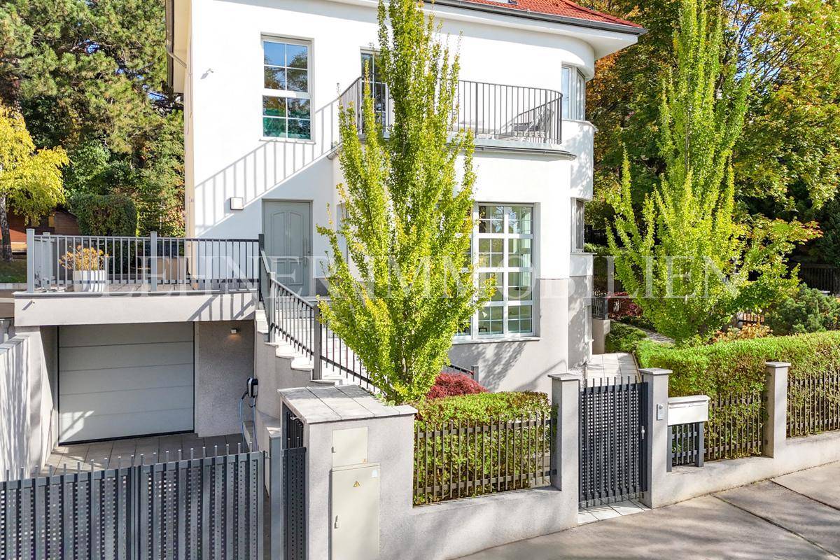 Seitliche Ansicht der Stadtvilla mit Garagenzufahrt, Außentreppe und Balkon.
