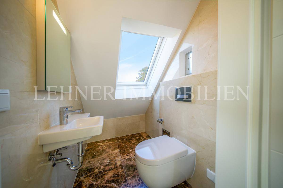 Modernes Gäste-WC mit Dachfenster, Wand-WC und kleinem Waschbecken unter der Dachschräge.