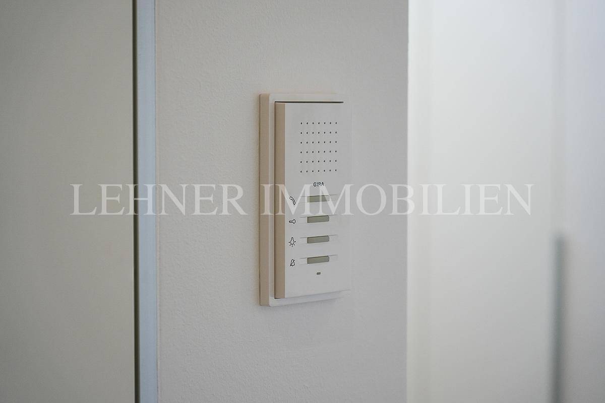 Detailansicht einer modernen Gegensprechanlage an einer hellen Wand.