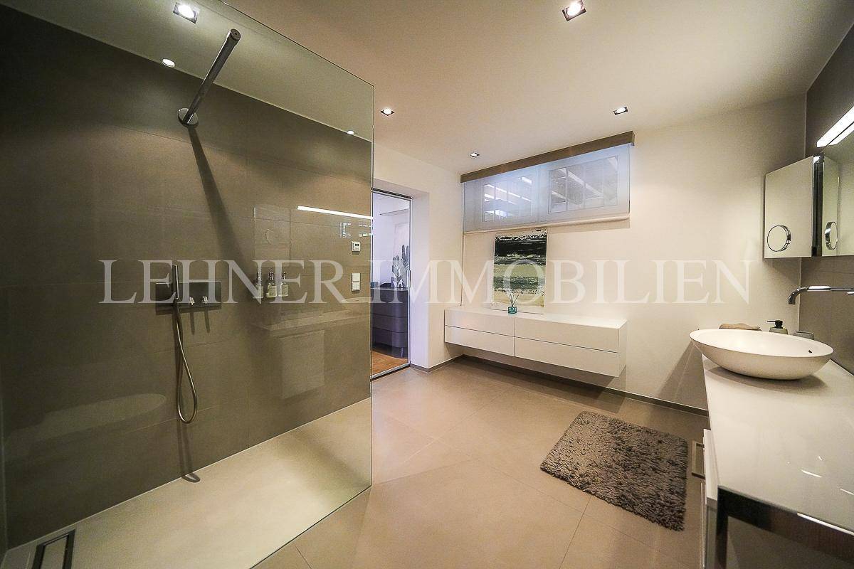 Helles Badezimmer mit großer begehbarer Dusche, modernem Waschtisch und Fenster für Tageslicht.