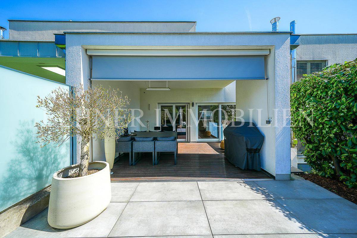 Überdachte Terrasse mit Holzboden, Essbereich und Grill, ideal für Mahlzeiten im Freien.