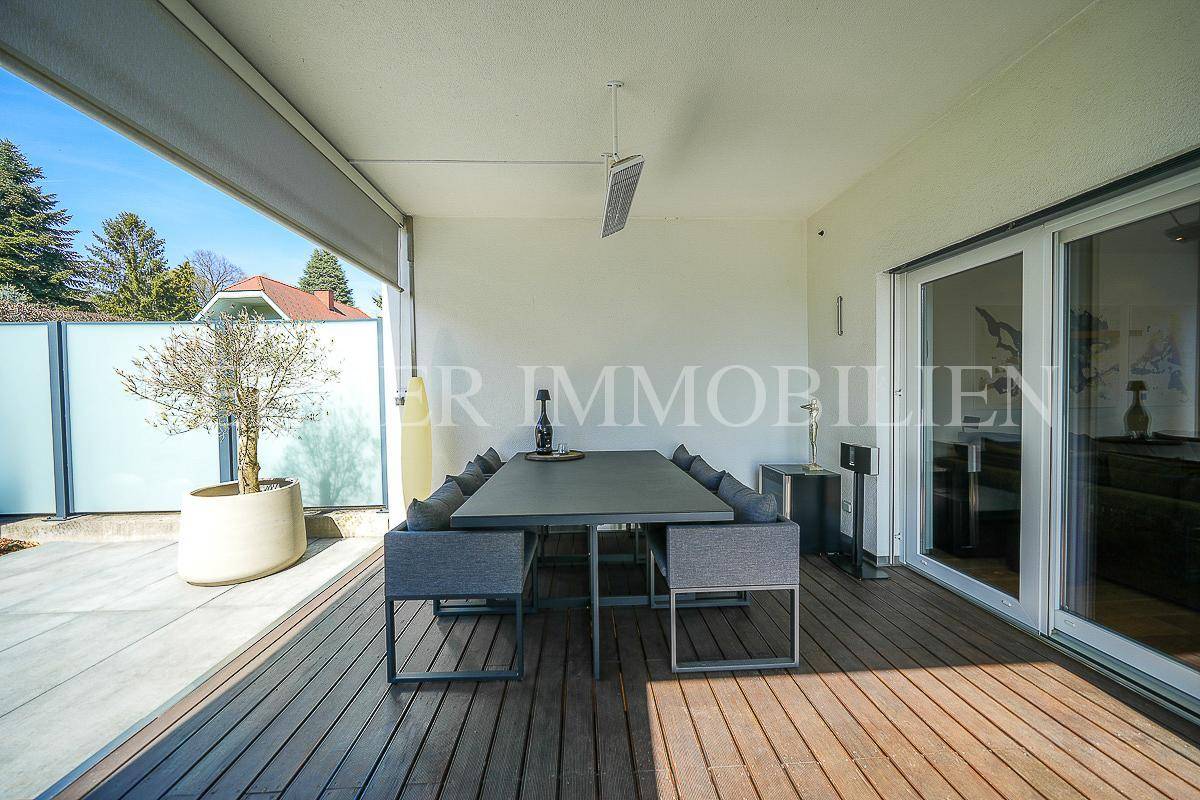 Überdachte Terrasse mit modernem Esstisch und Stühlen, ideal für Mahlzeiten im Freien.