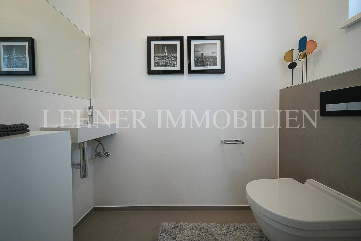 Modernes Gäste-WC mit wandhängender Toilette und minimalistischem Waschbecken.