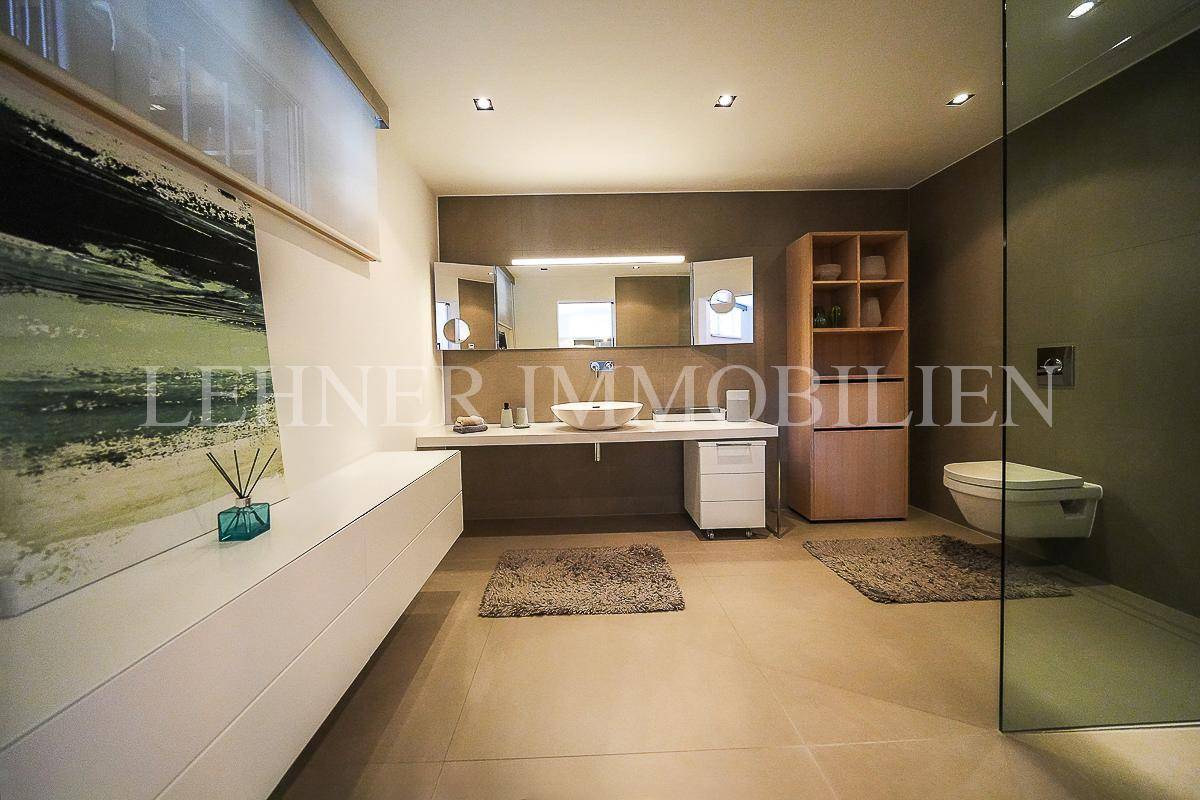 Geräumiges, modernes Badezimmer mit großem Waschtisch, Aufsatzwaschbecken und begehbarer Dusche.