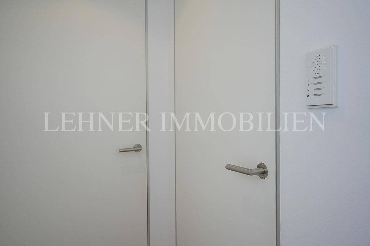 Zwei weiße Türen mit modernen Griffen und einer Gegensprechanlage im Flurbereich.