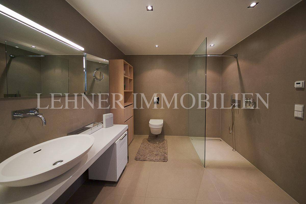 Elegantes Badezimmer mit minimalistischem Design, Aufsatzwaschbecken und bodengleicher Dusche.