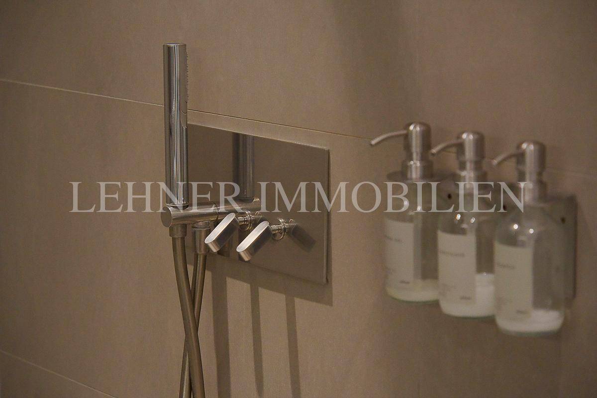 Detailaufnahme einer modernen Duscharmatur und praktischer Seifenspender in der Dusche.