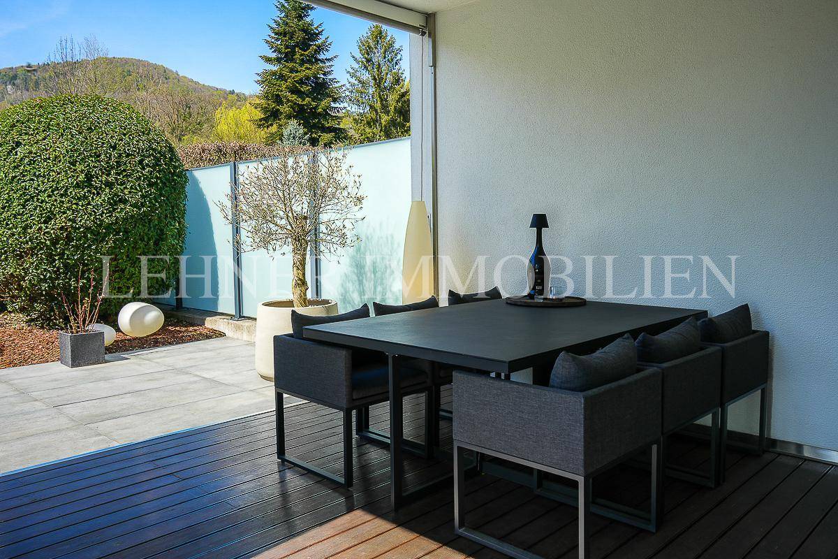 Sonniger Essbereich auf der Terrasse mit Blick auf den gepflegten Garten und die umliegende Landschaft.