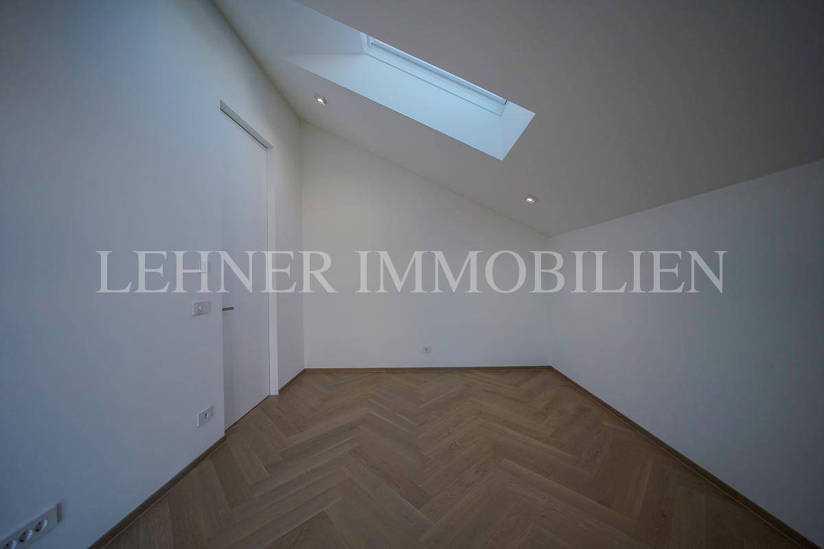 Geräumiger Raum mit Fischgrätparkett, schräger Decke und Dachfenster, ideal für vielseitige Nutzung.