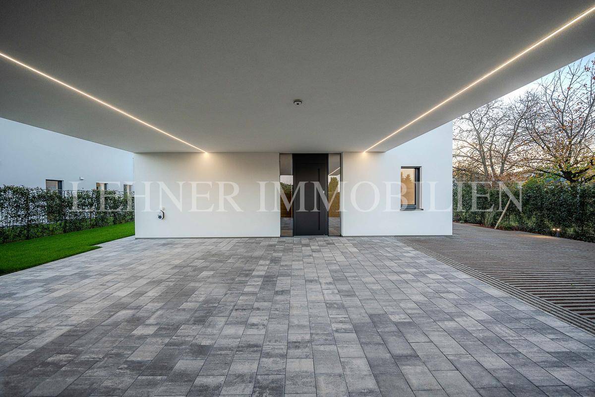 Geräumiger Carport-Bereich mit moderner Pflasterung und minimalistischem Hauseingang.