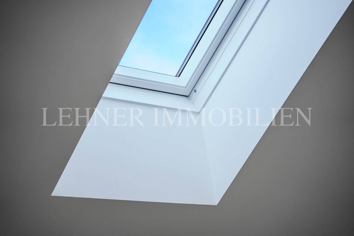 Detailaufnahme eines modernen Dachfensters in einer weißen Decke, das Tageslicht hereinlässt.