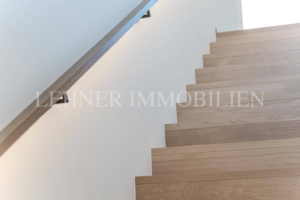 Moderne Holztreppe mit schlichtem Geländer, die verschiedene Ebenen verbindet.