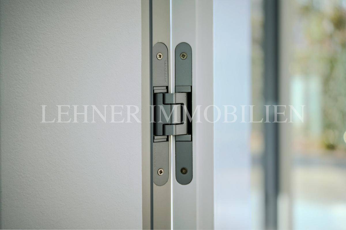 Detailansicht eines modernen, verdeckten Türscharniers an einer weißen Tür.