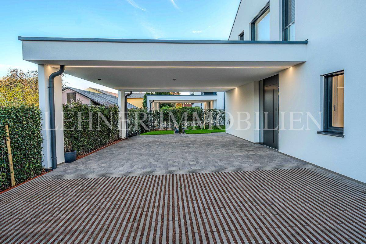 Überdachter Carport-Bereich mit moderner Beleuchtung und Zugang zum Hauseingang.