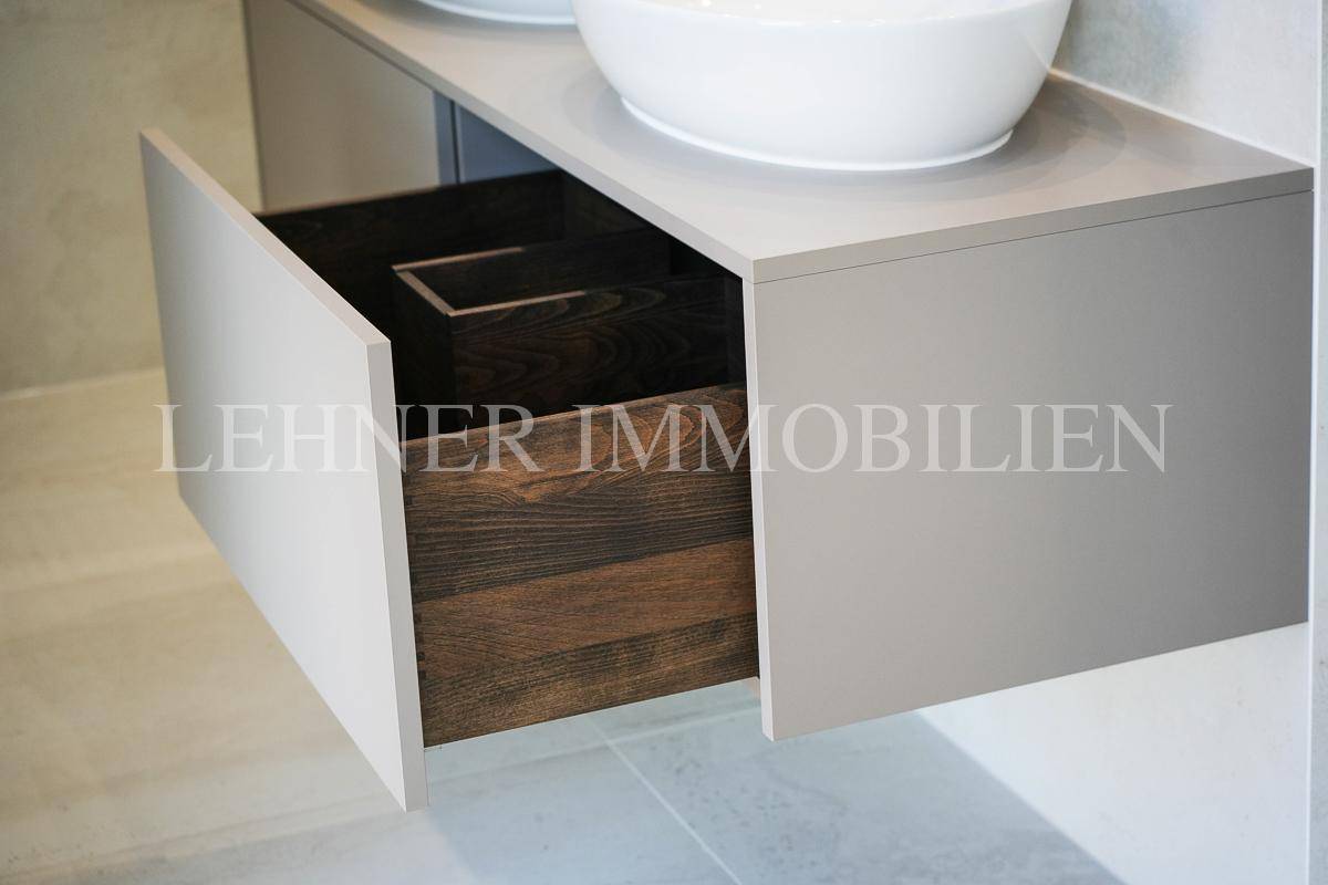 Offene Schublade eines modernen Badezimmermöbels mit dunklem Holzinterieur.