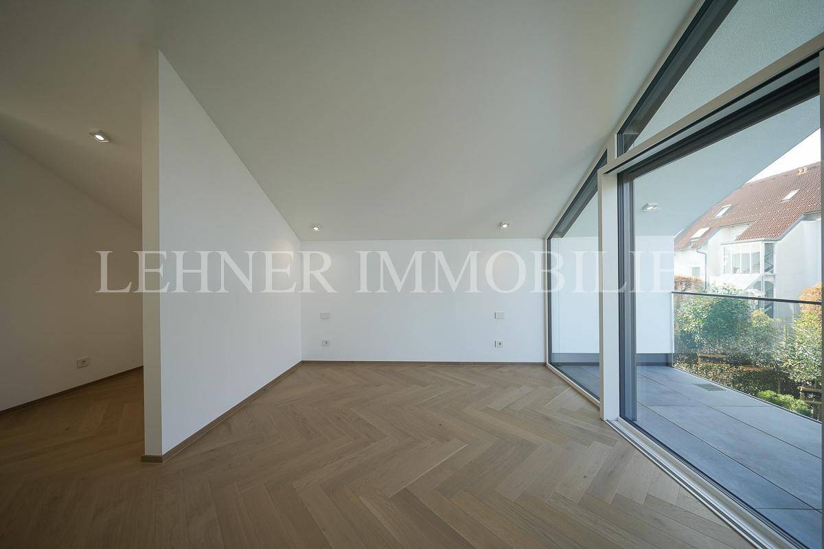 Großes Schlafzimmer mit Fischgrätparkett und bodentiefen Fenstern zum Balkon.