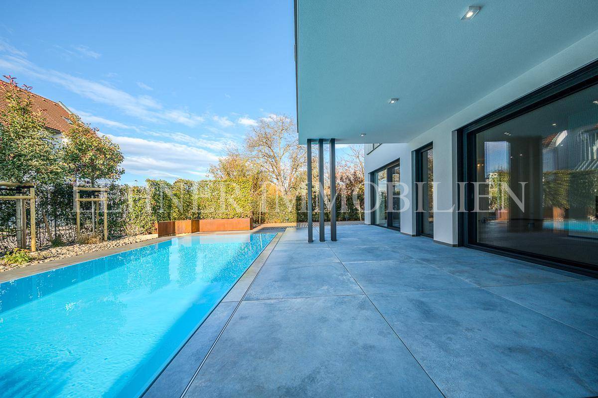 Großzügige Terrasse mit direktem Zugang zum Pool und Blick auf den Garten der modernen Villa.